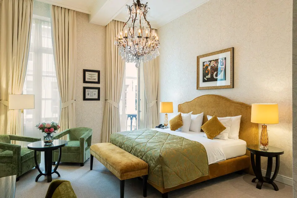 A deluxe room at the Grand Hotel Casselbergh with a double bed, armchairs and a chandelier