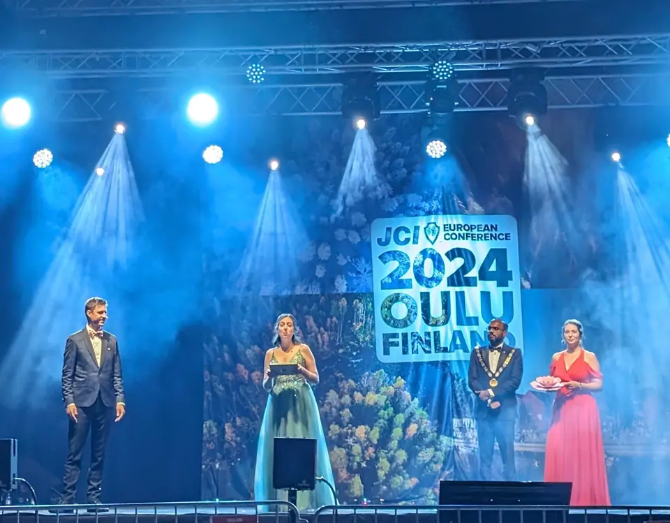 Four presenters on a blue-lit stage in front of the 2024 Oulu Finland backdrop during the awards ceremony