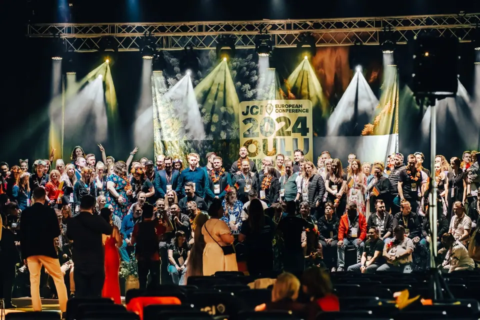 Crowd of delegates cheering in front of a stage with the JCI European Conference 2024 Oulu sign