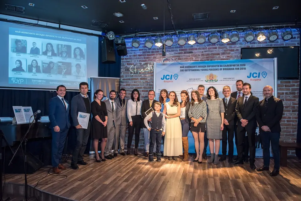 About thirty award winners and guests lined up on stage in front of a JCI TOYP Bulgaria backdrop