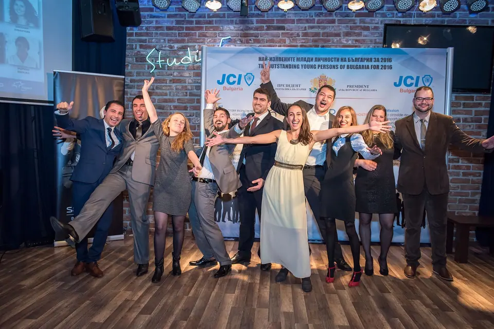 TOYP Bulgaria participants posing playfully on stage in front of a JCI banner