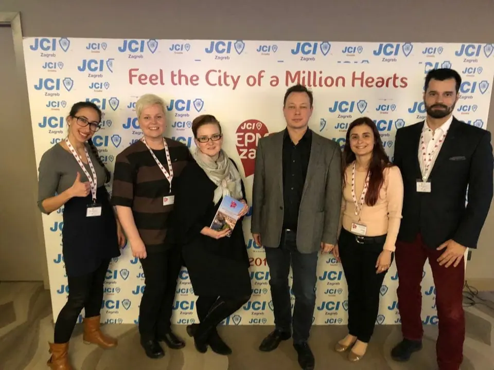 The JCI European Development Council team standing in front of a JCI backdrop reading Feel the City of a Million Hearts