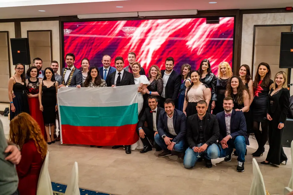 JCI Bulgaria members holding a Bulgarian flag in front of a red-lit stage at the Balkan Conference