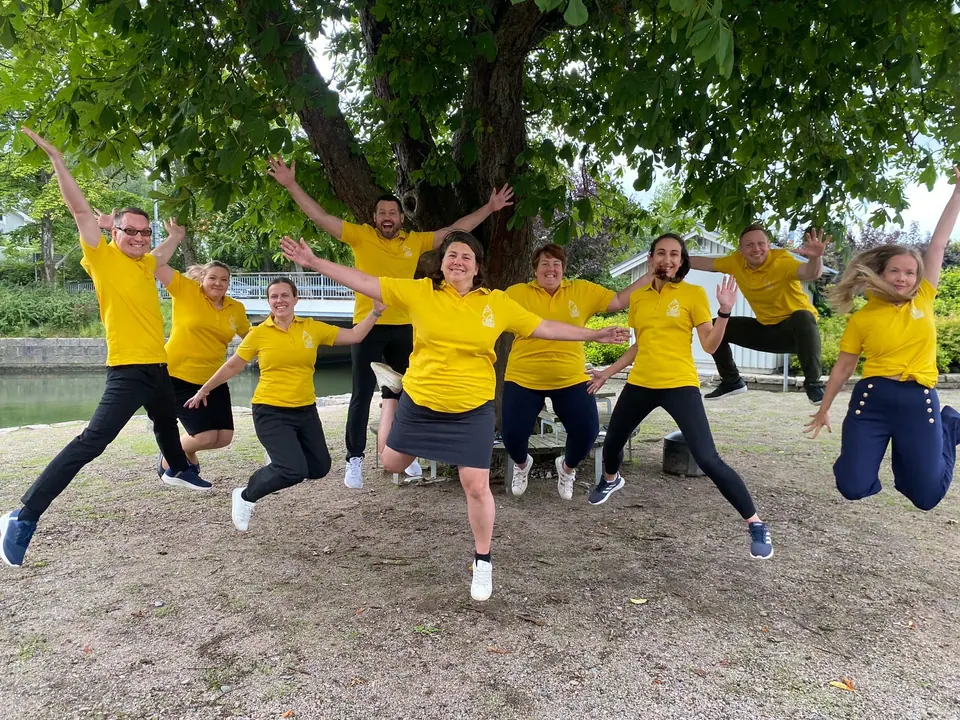 Participants in yellow T-shirts jumping for the camera outdoors at the JCI European Academy