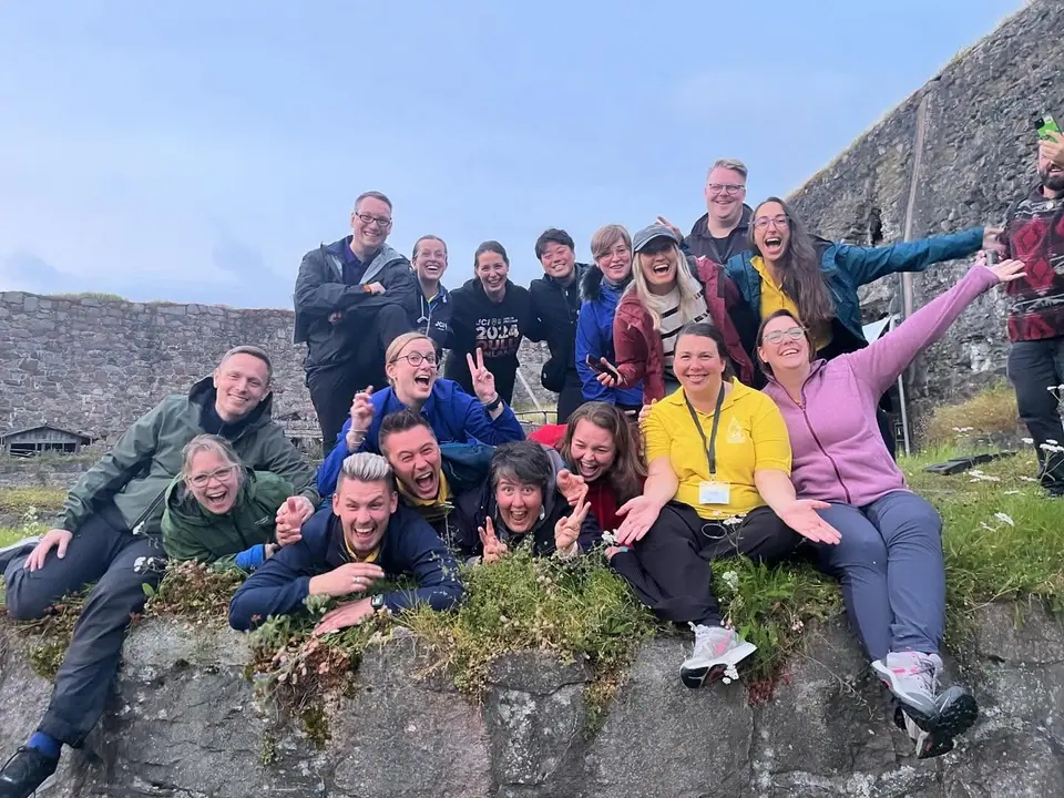 Participants of the JCI European Academy posing and laughing on a rocky hillside