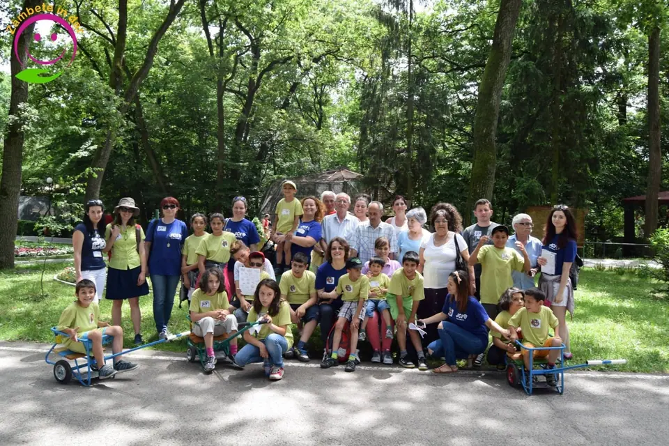 A large group of children, volunteers and members posing in a park
