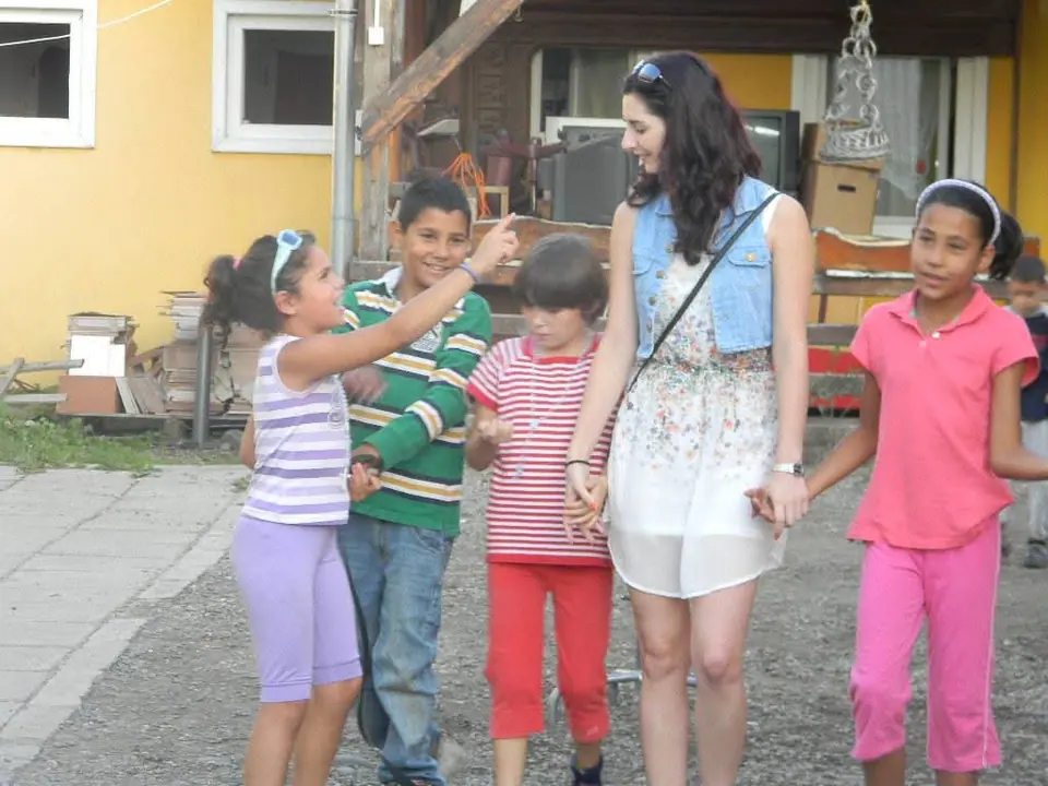 A woman with four children on a courtyard, smiling at the camera