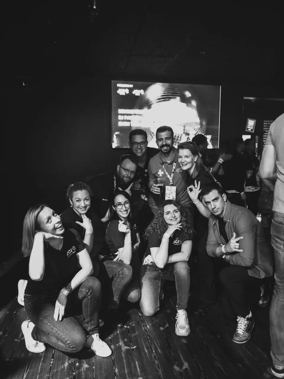 A black-and-white photo of a group of young people posing in a dark venue