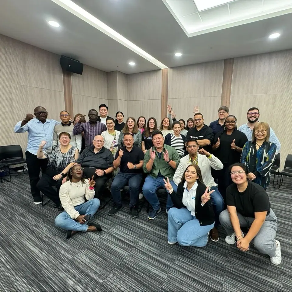A large group of WHQ team members crouching and standing together in a meeting room