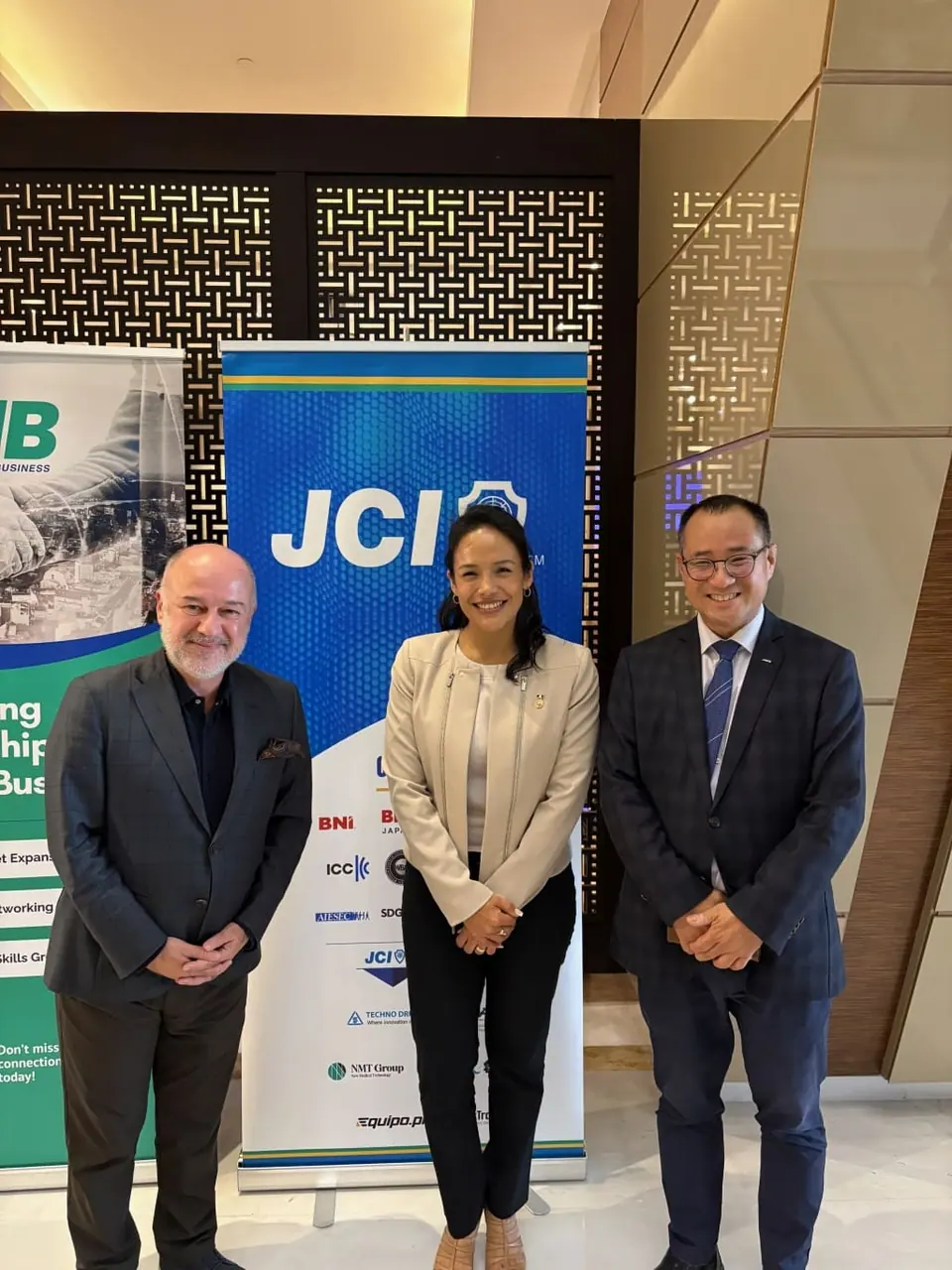 Three people standing in front of a JCI banner at an event in Tunis