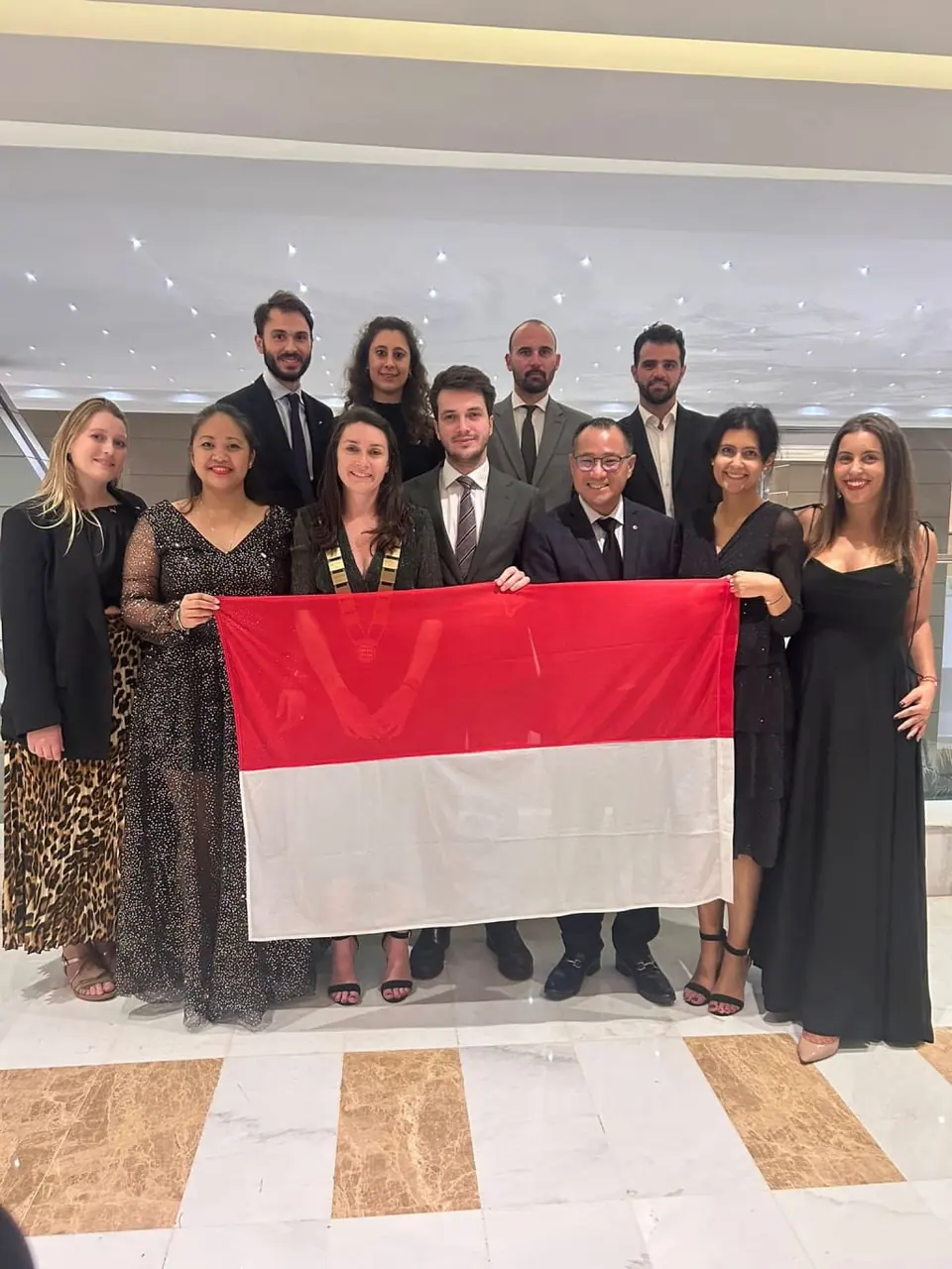 The JCI Monaco delegation posing with a Monaco flag at the 2025 World Congress in Tunis