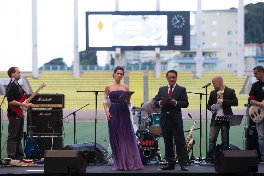 A man and a woman on a stadium stage with a band behind them at the European Conference opening ceremony