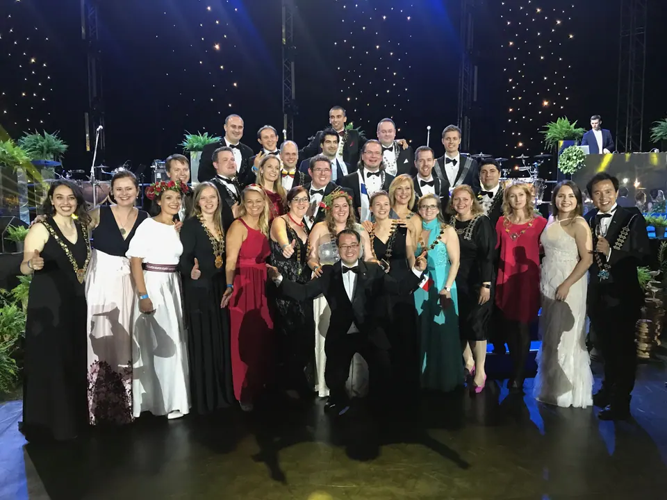 A large group of National Presidents in evening wear on a stage in Riga