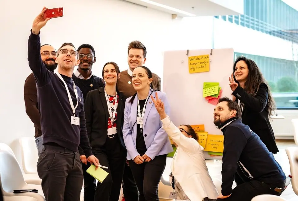 Group of JCI members taking a selfie together in front of a whiteboard with sticky notes