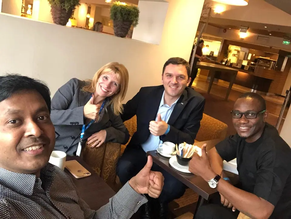 Four men and women taking a selfie over coffee in a lounge