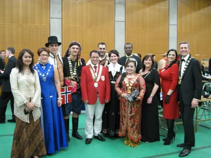 A group of about fifteen people in national and traditional costumes posing in a hall
