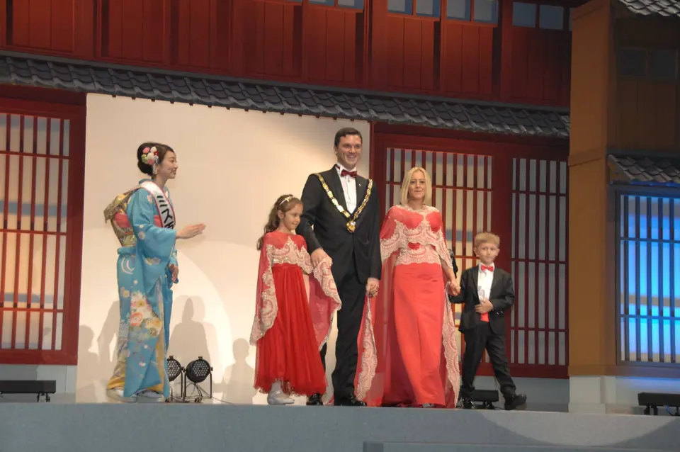 Four people in traditional dress and a man in a chain of office on a stage at the World Congress