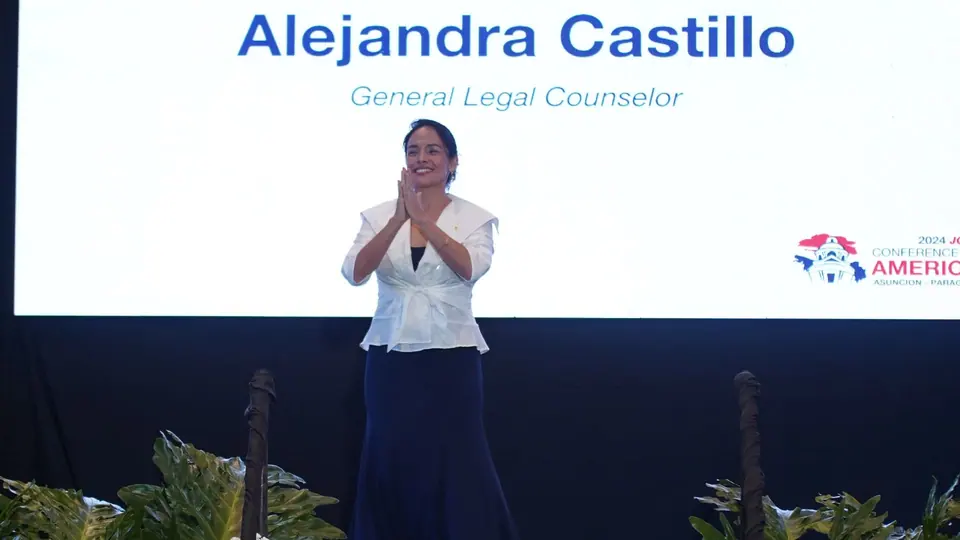 Alejandra Castillo clapping on stage in front of a slide naming her as General Legal Counsel