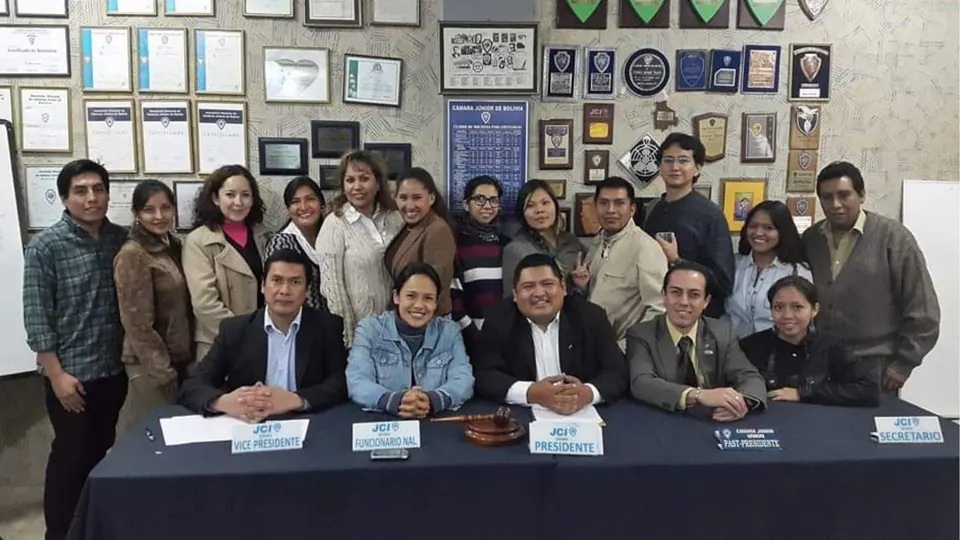 About a dozen members seated and standing behind a conference table, posing for a group photo