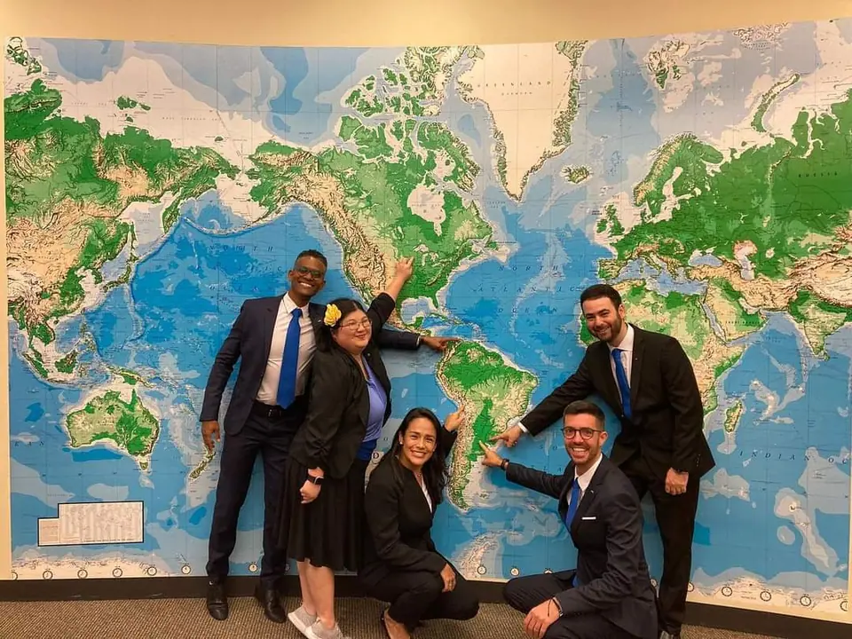 Five JCI leaders pointing at places on a large world map