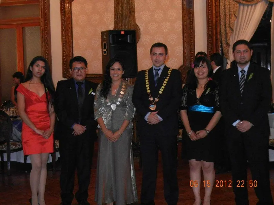 Seven people in formal wear, one with a chain of office, standing in a row at a gala