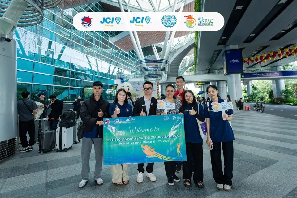 A group holding a welcome banner in an airport arrivals hall
