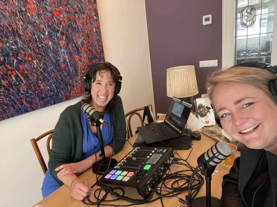 Two women recording a podcast with headphones and a mixing desk