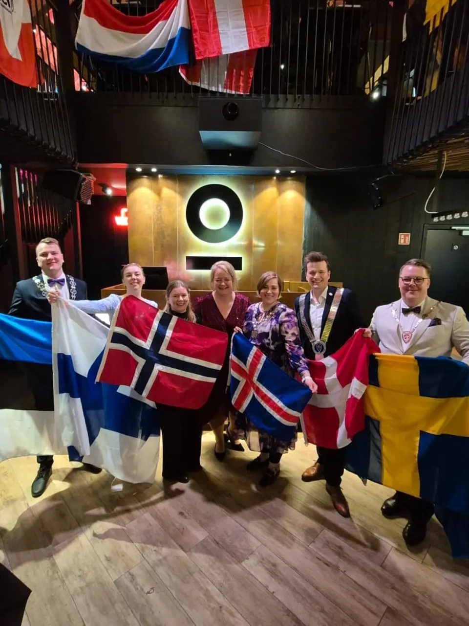 A group holding Nordic and European flags in a bar