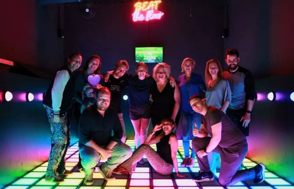 A group posing on a colourful lit dance floor in a club