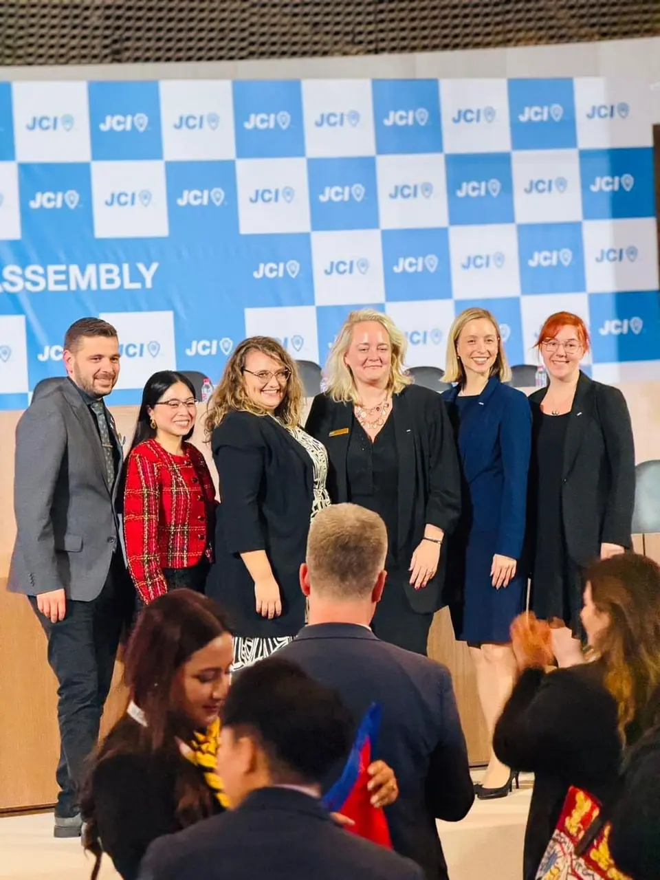 JCI members in front of a JCI backdrop at an assembly