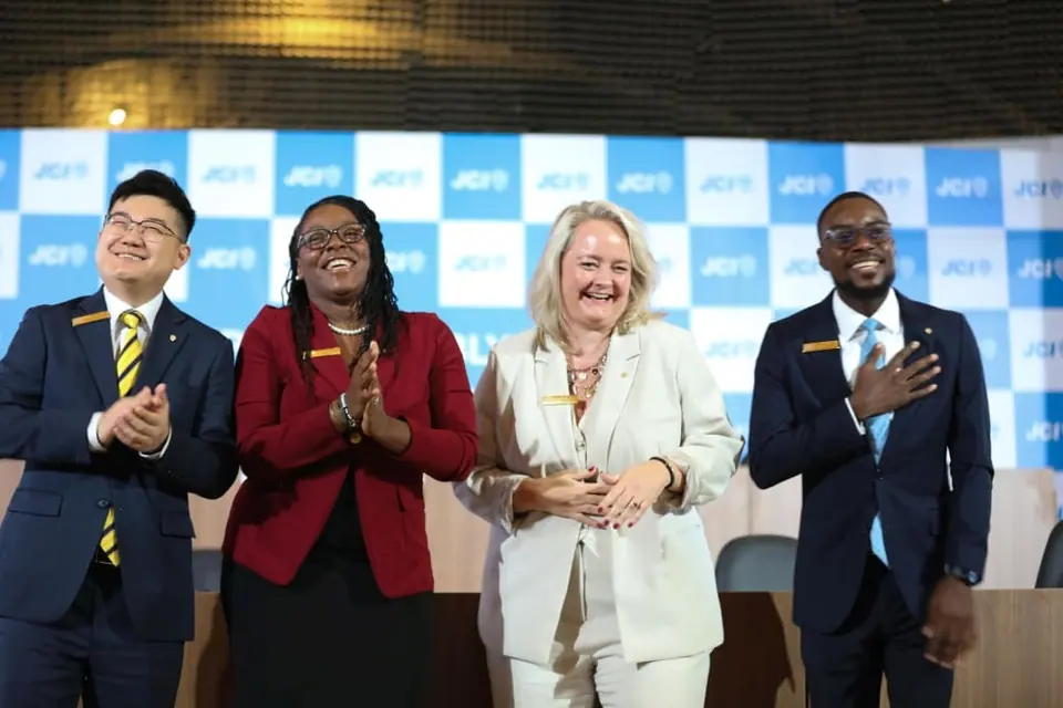 Four JCI leaders in matching blazers smiling in front of a JCI backdrop
