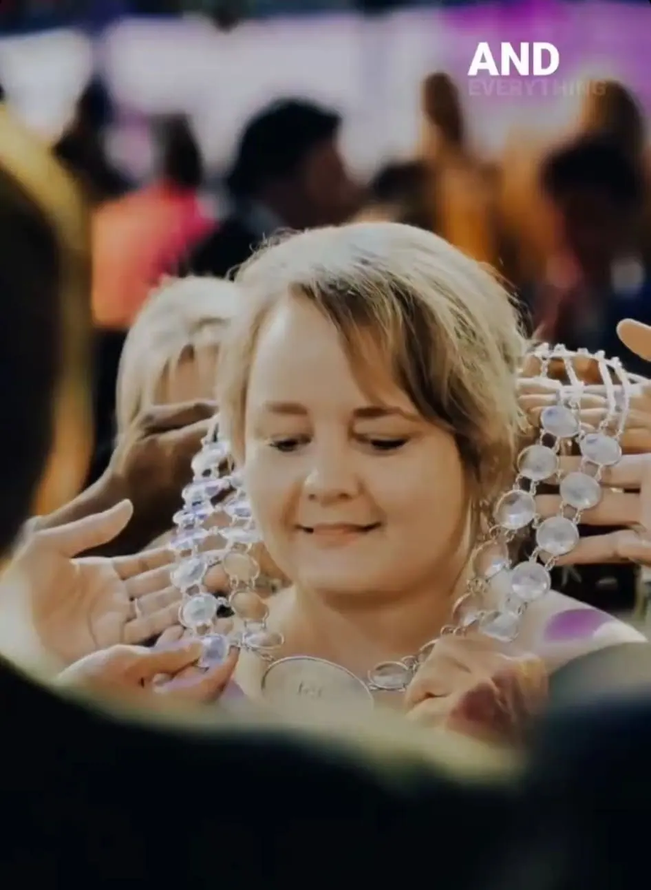 A smiling woman holding a strand of bead necklaces, with the word AND in the corner