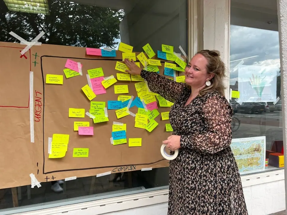 A woman in a patterned dress sticking notes on a large paper planning board