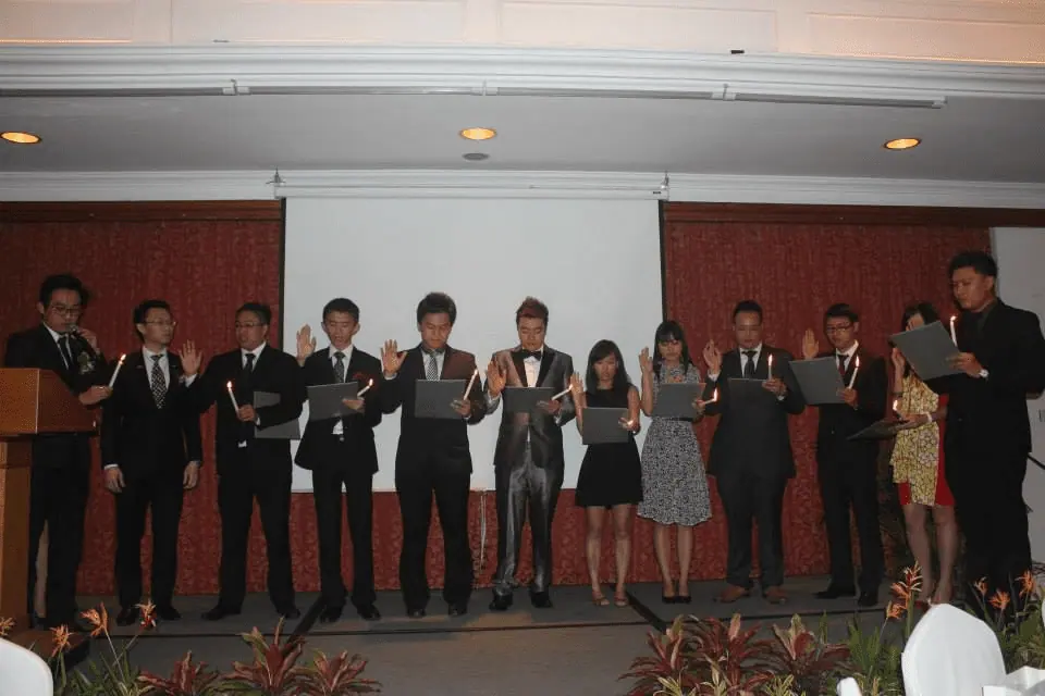 Members in dark clothes lined up on a stage during an induction ceremony