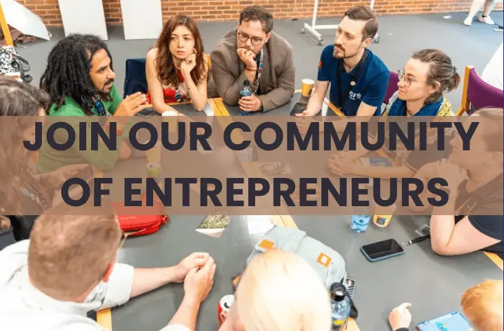 Group of people around a table in conversation, with the words Join our community of entrepreneurs across the picture
