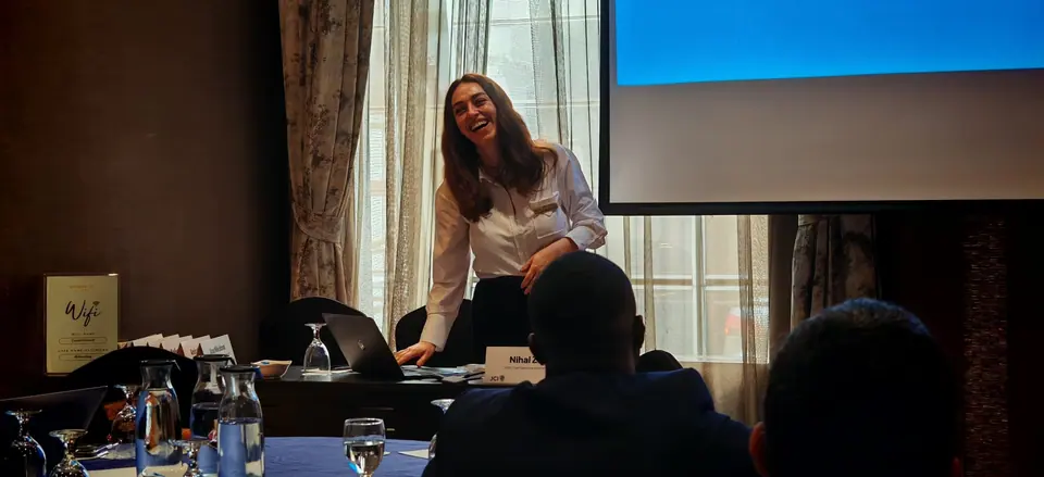 A woman presenting to a seated audience in a hotel conference room