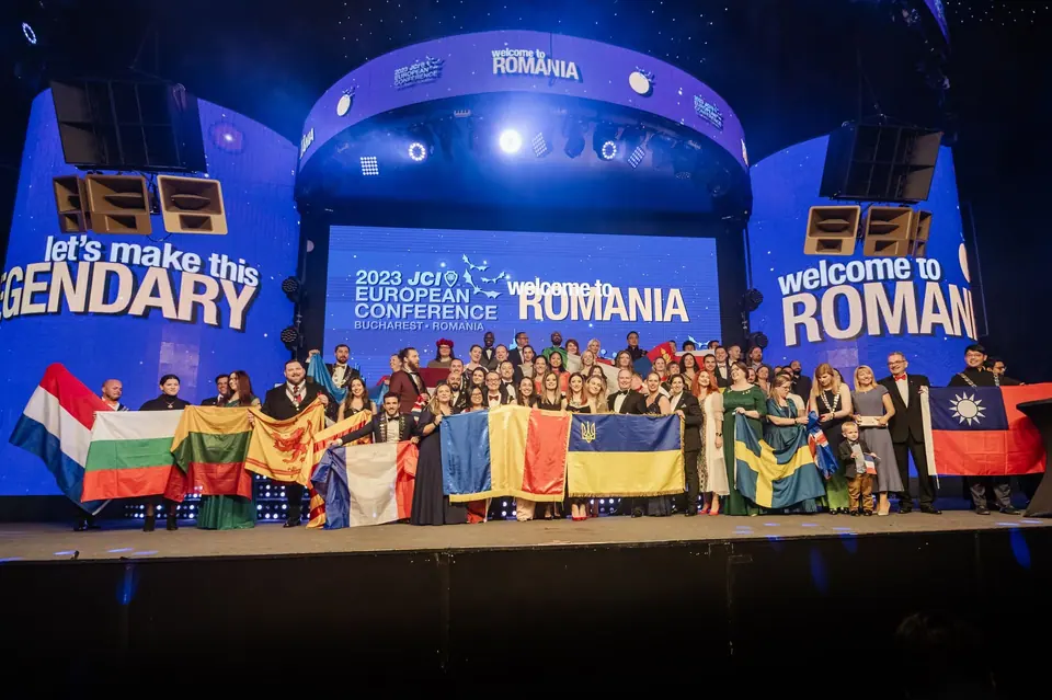 A large group with national flags on the stage of the 2023 JCI European Conference in Romania