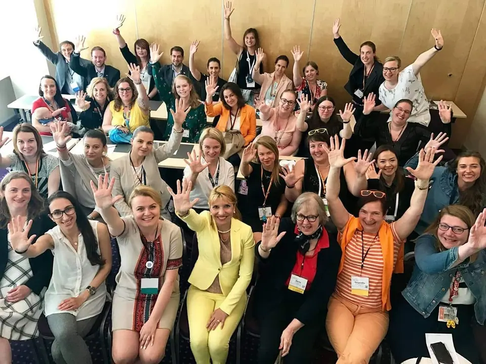 A large group of participants raising their hands and cheering in a seminar room