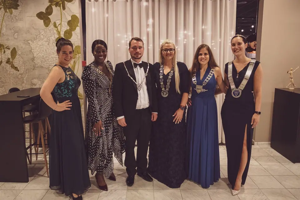 Six people in evening wear, four wearing chains of office, posing at a gala