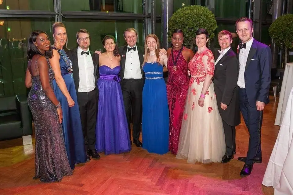 Ten people in gowns and dinner jackets posing at a gala