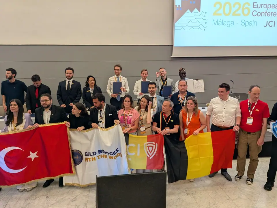 A crowd of JCI members posing with Turkish and Belgian flags and a JCI banner