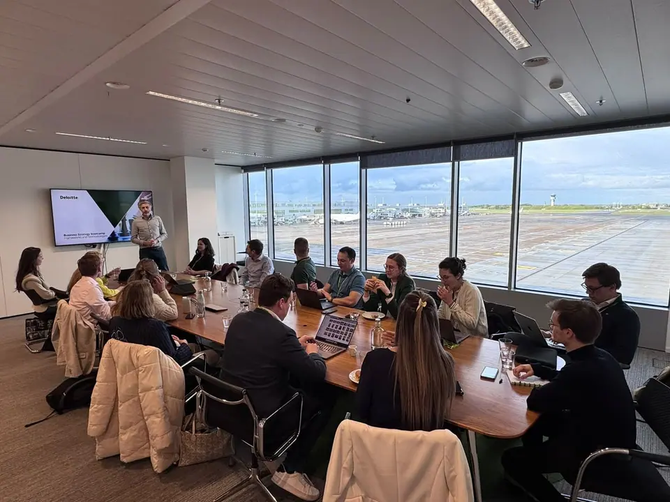 Participants seated around a long conference table in a room with large windows