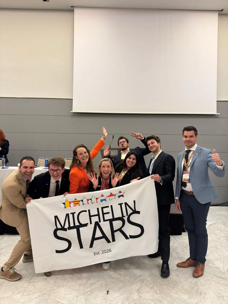 Smiling members holding up a banner reading Michelin Stars