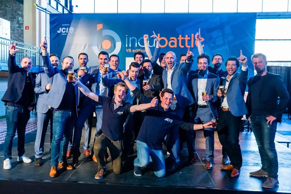 A cheering crowd of JCI members in front of an IncuBattle banner